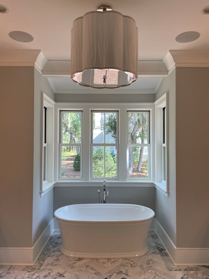 Elegant bathroom featuring a freestanding bathtub and large windows with outdoor view.